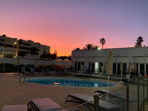 una piscina frente a un edificio con puesta de sol en Bungalows Islas Paraiso, en Playa del Inglés