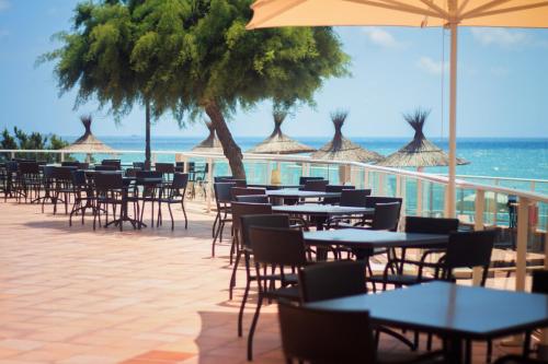 a beach area with tables, chairs and umbrellas at Hotel Servigroup Galua in La Manga del Mar Menor
