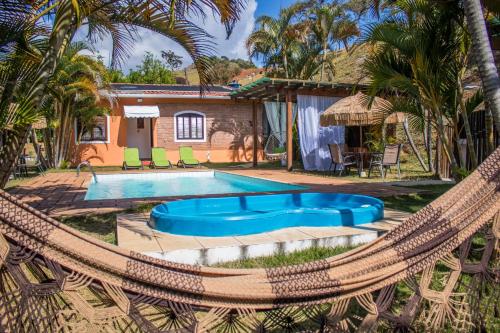a pool with a hammock and a house at Pousada Sonho Meu in Itanhandu