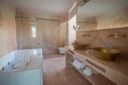 Hotel República Boutique Hotel في تومار: حمام كبير مع مغسلتين وحوض استحمام وحوض استحمام