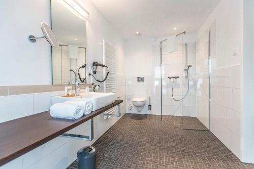 La salle de bains blanche est pourvue d'un lavabo et d'une douche. dans l'établissement Hotel Am Markt, à Ennigerloh