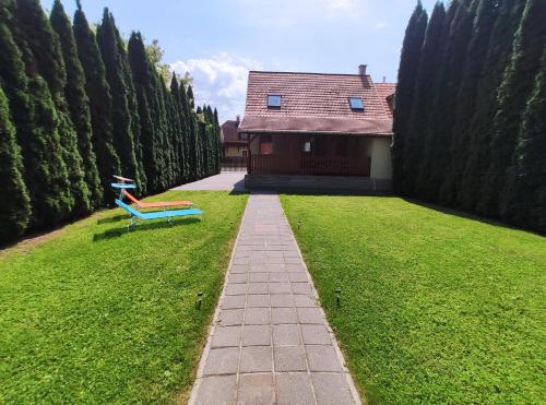 a blue bench sitting in the grass next to a house at Apollo Vendégház in Bogács