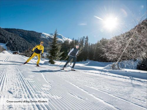 two people cross country skiing down a snow covered slope at Grischa - Das Hotel Davos in Davos