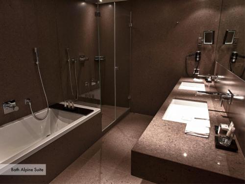 bagno con 2 lavandini, vasca e doccia di Grischa - Das Hotel Davos a Davos