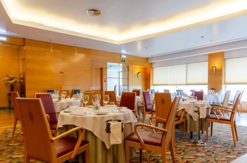 a dining room with tables and chairs with white tablecloths at Hotel Roma in Lisbon