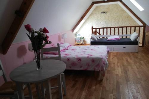 les alouettes في Leschelles: غرفة نوم بسرير وطاولة مع إناء من الورد