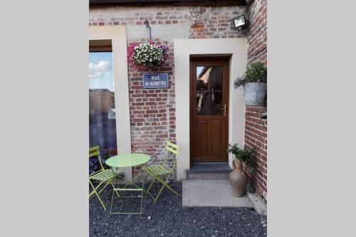 a brick building with a table and chairs in front of a door at les alouettes in Leschelles