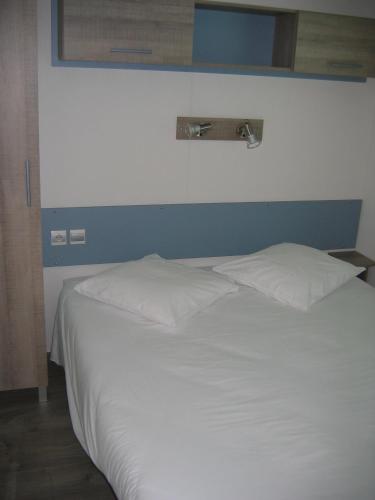une chambre avec un lit blanc avec un mur bleu dans l'établissement Le mobilhome Chez Camille, à Veynes