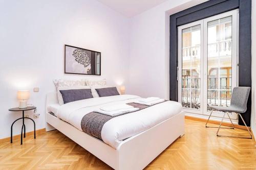 biała sypialnia z dużym łóżkiem i krzesłem w obiekcie Encantador Apartamento en Chueca junto a Gran Vía, Infantas 1-1 by Batuecas w Madrycie