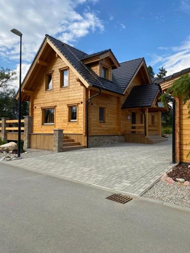 a large wooden house with a large driveway at Rezidencia Woodchalet in Veľká Lomnica