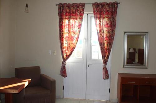 a living room with a door with curtains and a couch at Hotel Gina in San Juan de los Lagos
