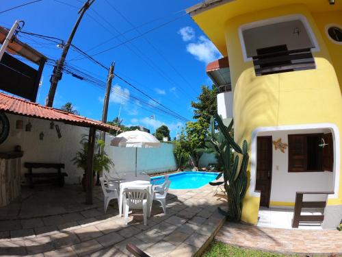 a villa with a swimming pool in front of a house at Aguamarinha Pousada in Porto De Galinhas