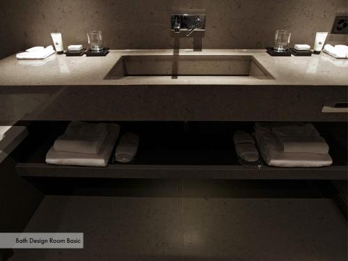 a bathroom with a sink and towels on a shelf at Grischa - Das Hotel Davos in Davos
