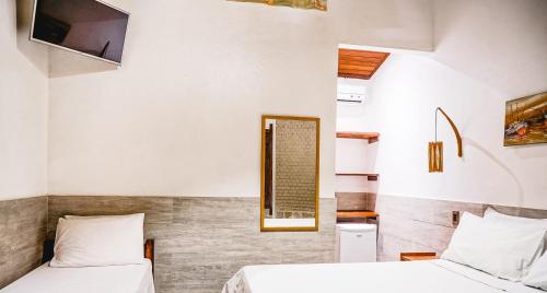 a bedroom with two beds and a mirror at Pousada El Capitan in Barra Grande