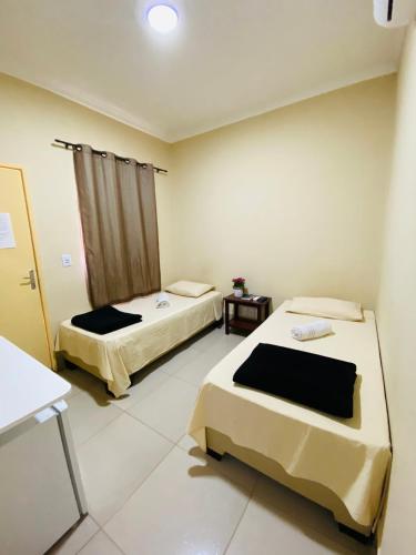 a room with two beds and a table in it at Hotel Pousada Marra in Catalão