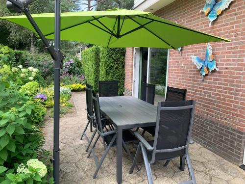 a table and chairs under a green umbrella at Mariposa in Otterlo