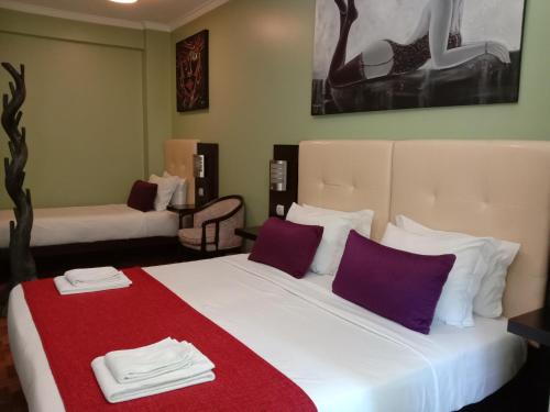 a hotel room with two beds with purple and white pillows at Faria Guimares Porto Centro in Porto
