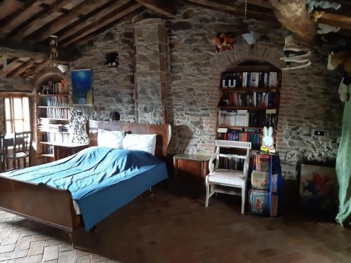 una camera con letto e parete in pietra di Attic with balcony at Locanda del Capo a Capannori