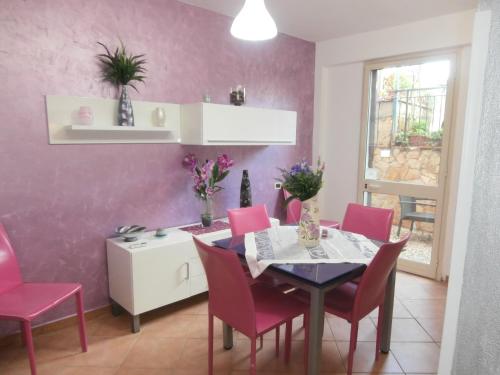 uma sala de jantar com paredes cor-de-rosa, uma mesa e cadeiras em Busalacchi B&B em Mondello