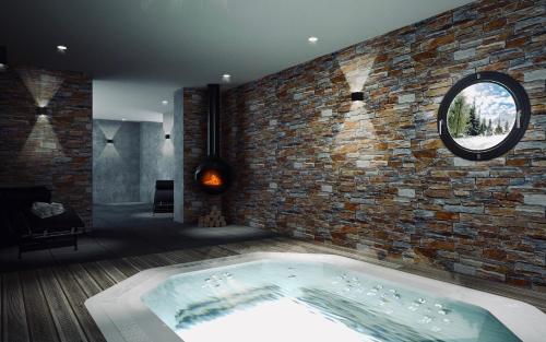 a bath tub in a room with a brick wall at Hôtel 16 | 150 Montagne & Spa Nuxe in Vars