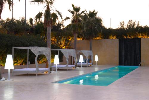 a pool with chairs and a table and palm trees at Casa De Campo in Mosciano SantʼAngelo