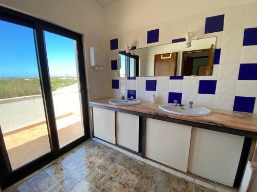 a bathroom with two sinks and a large window at Algarve Surf Hostel - Sagres in Sagres
