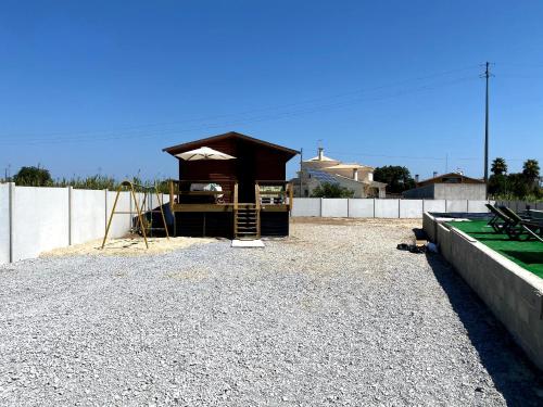 a small shelter in a gravel lot with a fence at Gothes Chalet Albertito in Ponte de Vagos