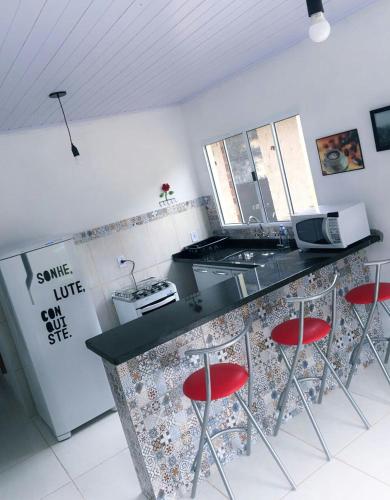 a kitchen with a counter with red stools in it at Recanto da Nice in Paraty