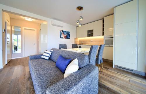 a living room with a blue couch and a kitchen at Villa Lungomare in Malinska