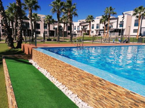 a swimming pool at a resort with palm trees at Bright bungalow Oasis Beach La Zenia in Orihuela