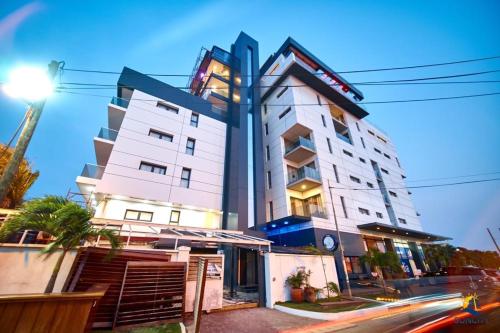 a tall white building with a sign on it at Suncity Hotel Apartment in Accra