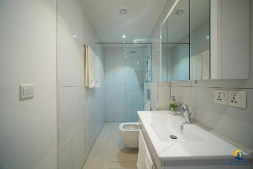 Suncity Hotel Apartment في آكرا: حمام أبيض مع حوض ومرحاض