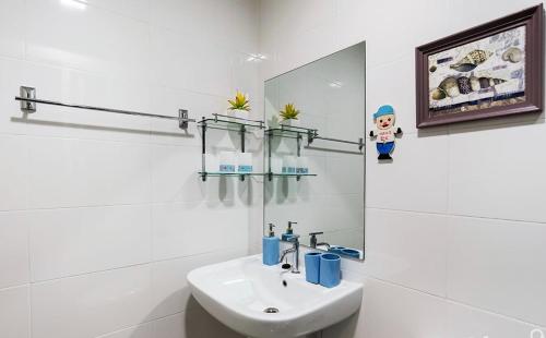 a white bathroom with a sink and a mirror at Lumpini Parkbeach Pattaya Pool View in Jomtien Beach