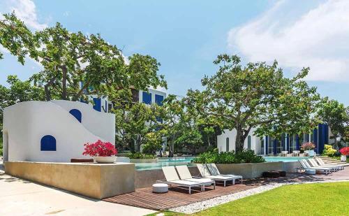 a swimming pool with lounge chairs and a building at Chelona huahin beachfront resort condo in Khao Tao