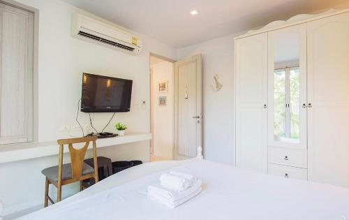 a white bedroom with a bed and a tv at Chelona huahin beachfront resort condo in Khao Tao