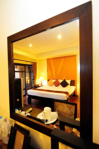 a mirror reflecting a bedroom with a bed in a room at Phunacome Resort in Dan Sai