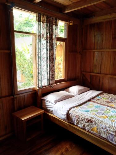 a bed in a room with a window at El Descanso in Mindo