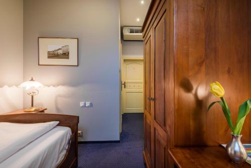 a hotel room with a bed and a vase with a flower at Dworek 1885 in Ostrzeszów