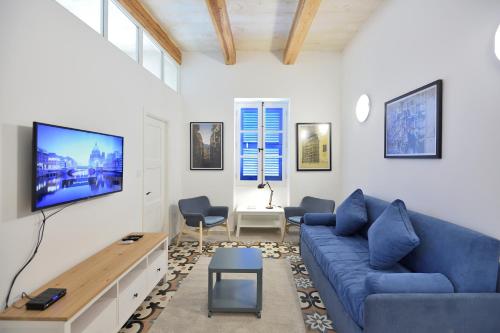 a living room with a blue couch and a tv at Grand Harbour Apartments in Il-Furjana