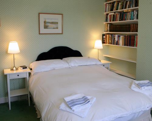 a bedroom with a bed with two lamps and bookshelves at Kirklands House Melrose Bed and Breakfast in Melrose