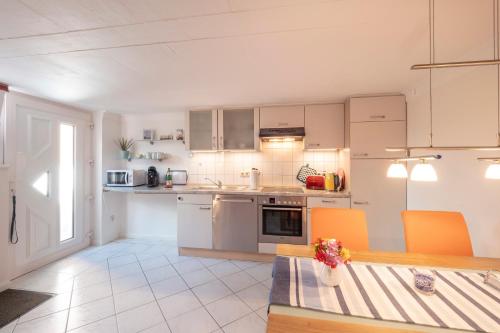 a kitchen with white cabinets and a table with orange chairs at FeWo Kleine Insel in Bad Segeberg