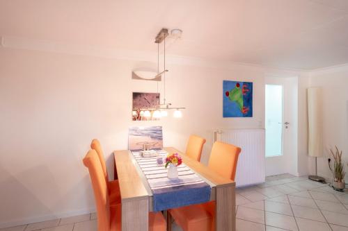 a dining room with a wooden table and orange chairs at FeWo Kleine Insel in Bad Segeberg