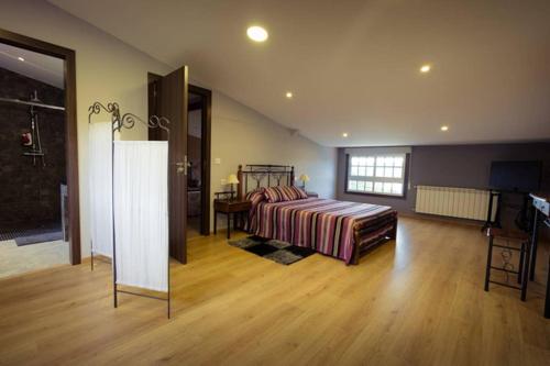 ein großes Schlafzimmer mit einem Bett und einem Holzboden in der Unterkunft Casamary Buhardilla in Pontevedra