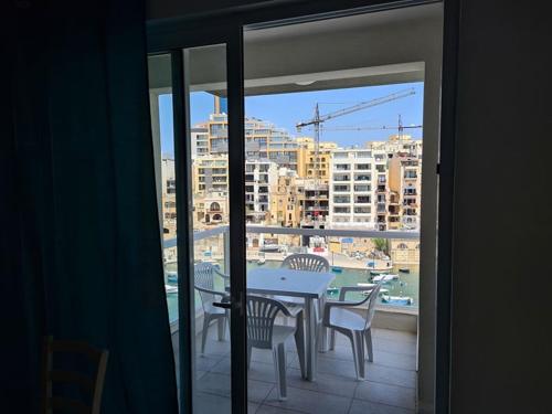 a table and chairs on a balcony with a view of a city at St Julians Bay Sea Front Apartments in St Julian's