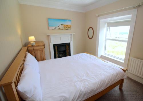 a bedroom with a white bed and a fireplace at Alcorn's Farmhouse in Rathmullan
