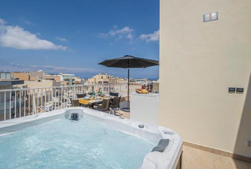 a hot tub on a balcony with an umbrella at Summer Breeze Penthouse with private Hot Tub & terrace with panoramic views, by Getawaysmalta in Mellieħa