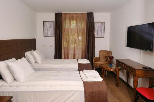 a hotel room with two beds and a flat screen tv at Hotel Splendid in Pleven