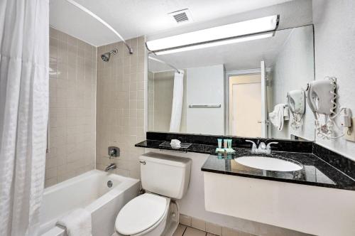 a bathroom with a toilet and a sink and a bath tub at Plaza Hotel Fort Lauderdale in Fort Lauderdale
