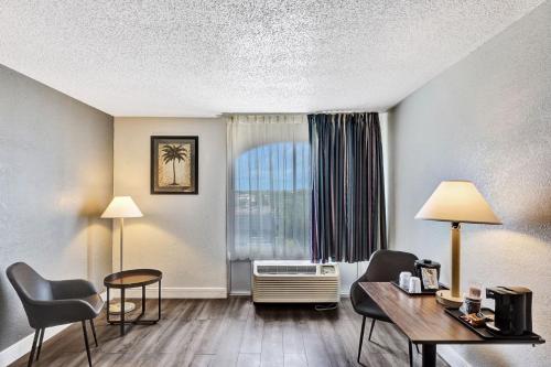a hotel room with a desk and chairs and a window at Plaza Hotel Fort Lauderdale in Fort Lauderdale