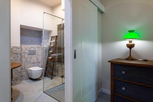 a bathroom with a toilet and a glass shower door at Aparthotel Zakątna B&B in Tarnów